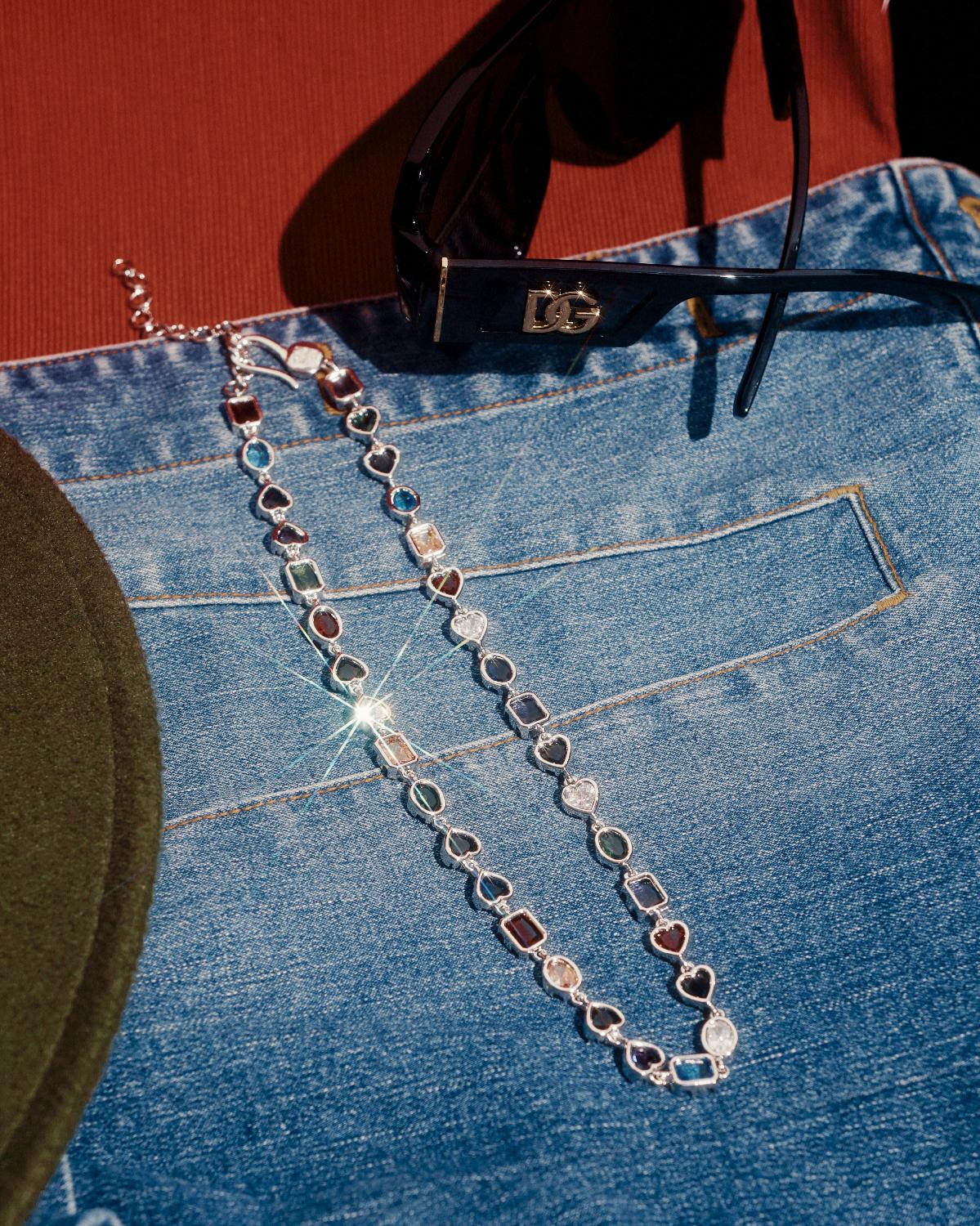 Close-up of ERA LINK Chain laid out on blue denim fabric, with a pair of black sunglasses positioned at the top of the frame - by Wrong Era